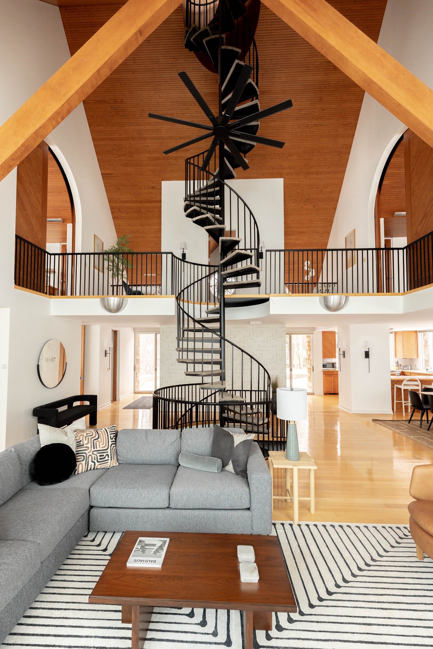 Spiral staircase centered in the room with wood ceiling, 1980's design brought back to life, featured on west elm and in WSJ Lighthouse bluff run by gathering place properties expertly designed by Savvy Design and Co.