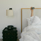 Bedroom with a bed and sculptural nightstand featuring a lamp and phone.