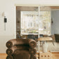 Modern living room with a brown armchair, wooden side table, and large windows.