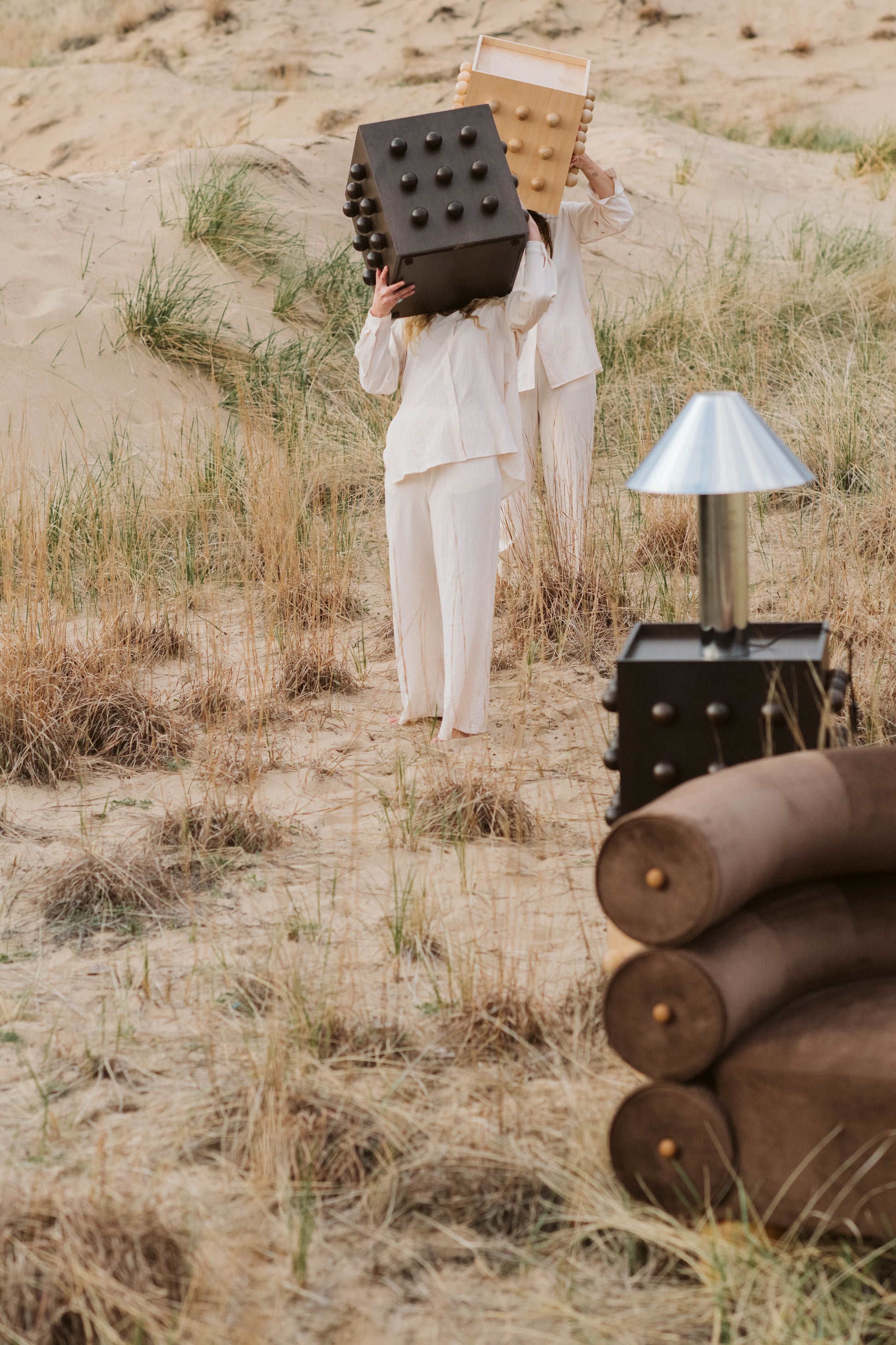 Person holding a large brown accent tables in a desert-like setting with various props around.